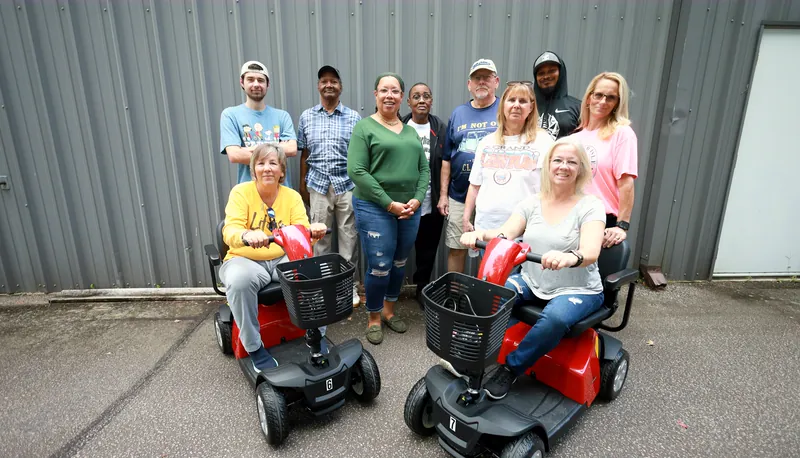 The Mobility Concepts crew outside the warehouse, two of them seated on red mobility scooters