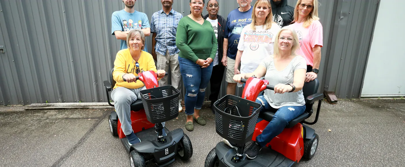 The Mobility Concepts crew outside the warehouse, two of them seated on red mobility scooters