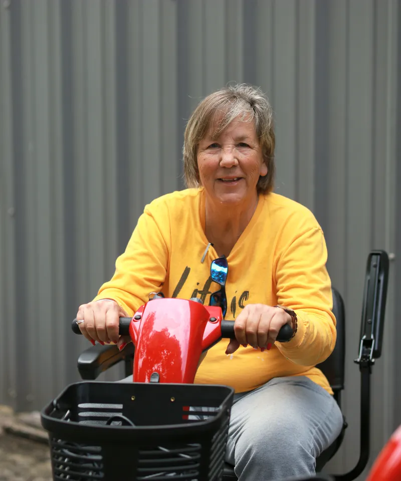 A Mobility Concepts crew member on a red mobility scooter