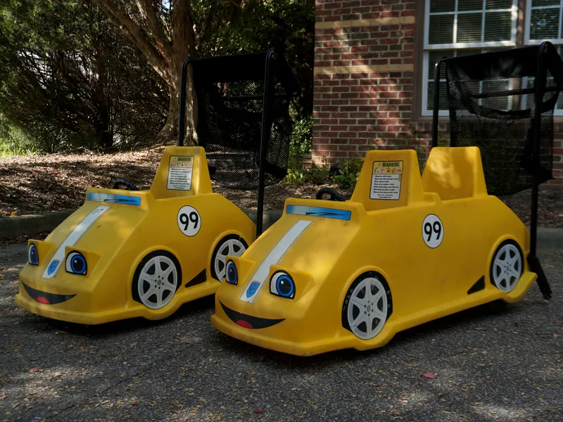 Two yellow CuddleCar child carts shaped like race cars