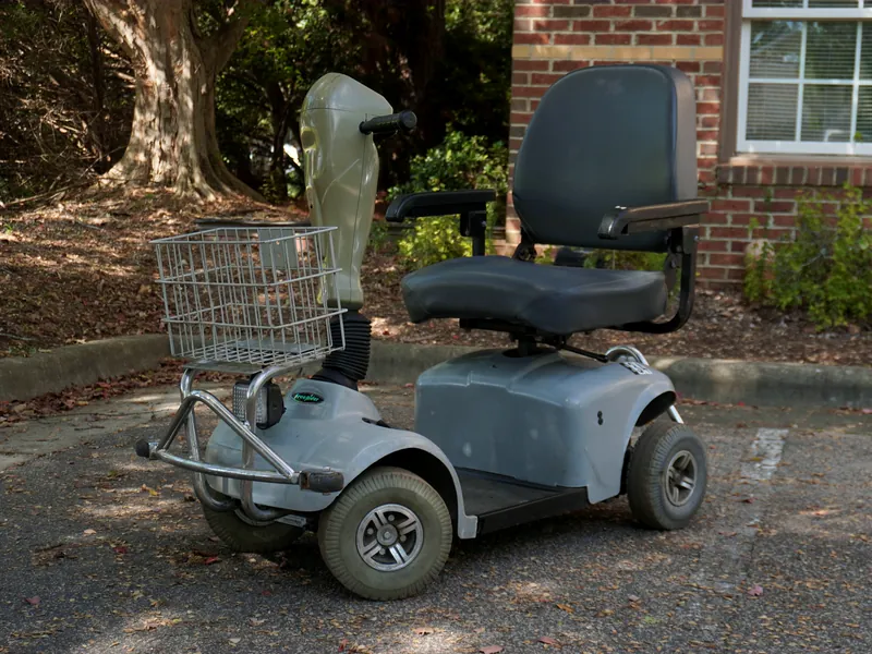 Gray four-wheel mobility scooter with a wire basket
