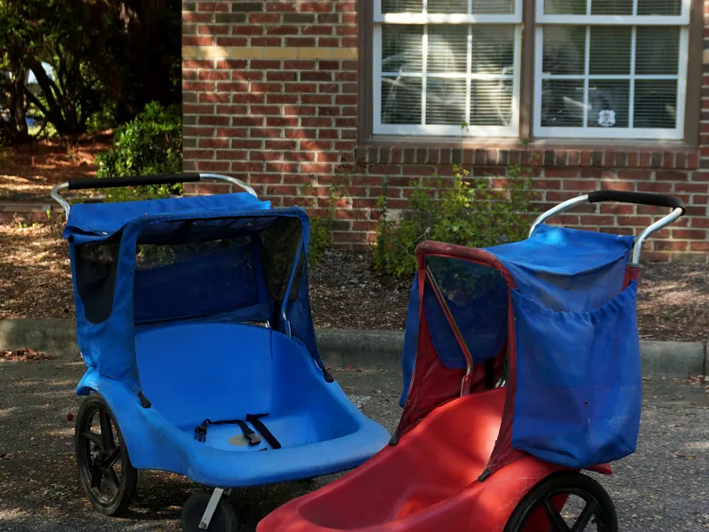A blue stroller and a red stroller, each with a canopy